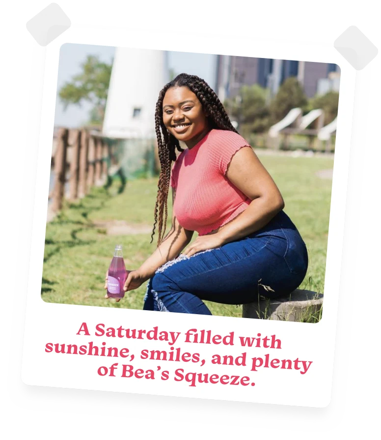 photo of a smiling young woman sitting outside holding a bottle of Bea's Squeeze lavender lemonade with the caption A Saturday filled with sunshine, smiles, and plenty of Bea's Squeeze